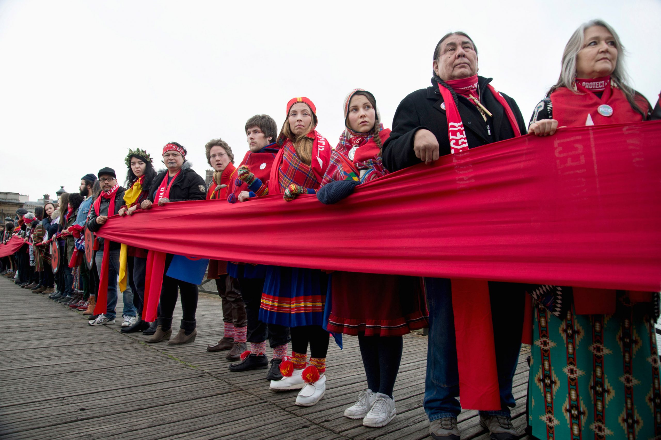 Des militants autochtones tiennent une « ligne rouge » sur le Pont des Arts lors de la Conférence sur le climat des Nations Unies, la COP 21, à Paris, en France. Les peuples autochtones et les communautés locales participent activement à des forums politiques et à des initiatives mondiales en matière de changement climatique. Photo : Jenny Matthews.