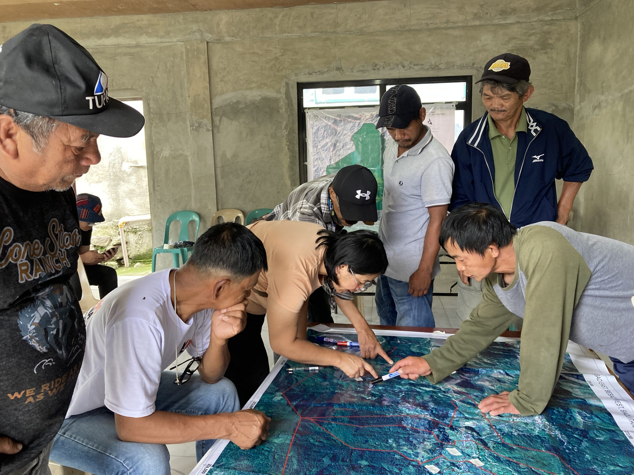 Community members of Payeo village gather around a map of their village and identify important community spots